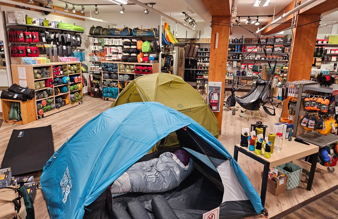 Tents set up on the store floor with sleeping bags and pads on shelves