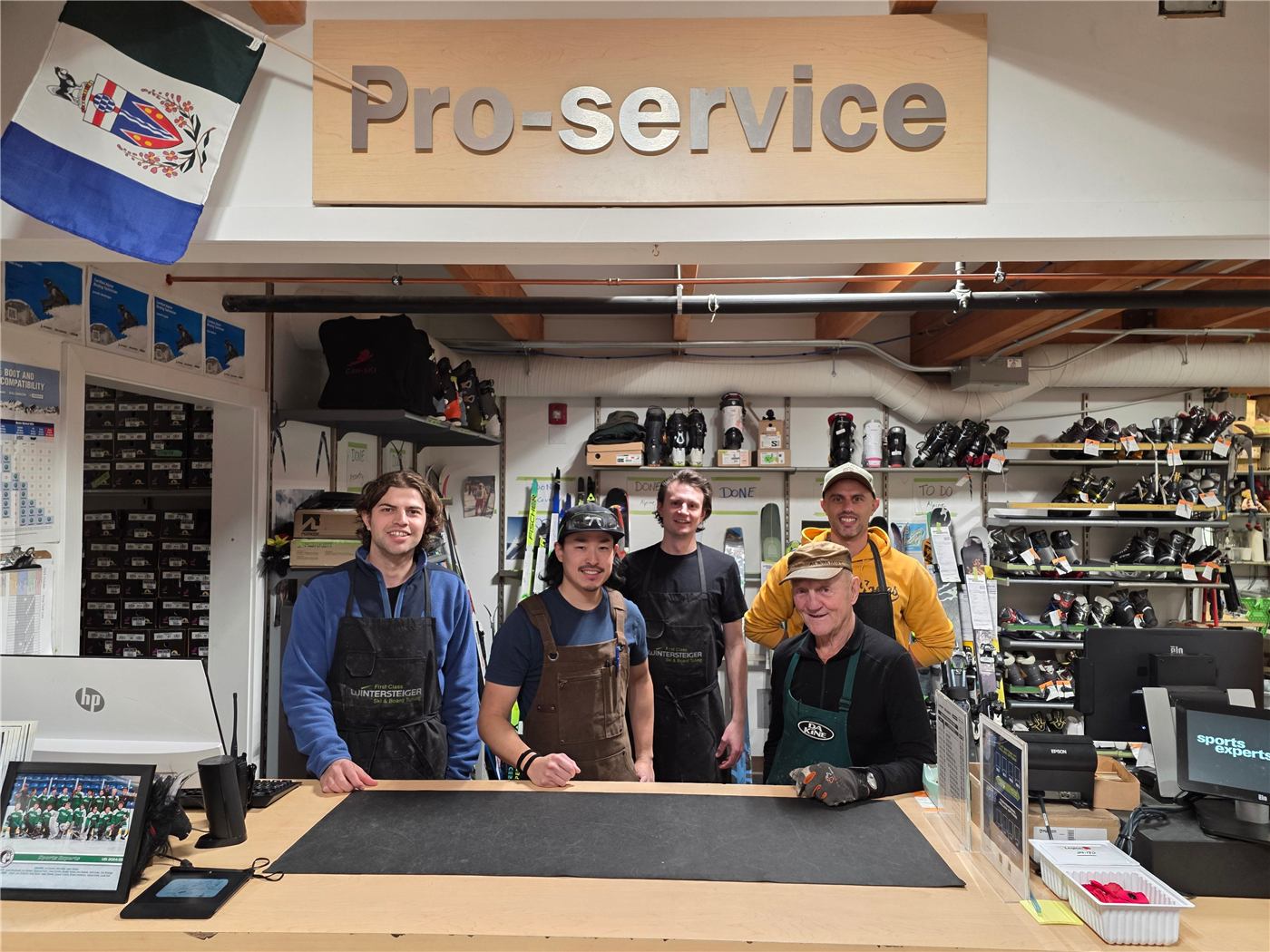 Five Pro Shop technicians standing at the service counter under a Pro-service sign