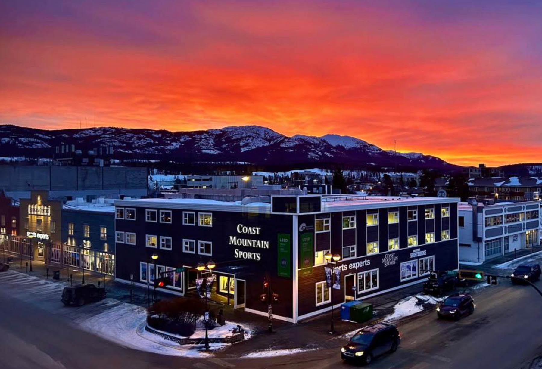 The Coast Mountain Sports building on Main Street at sunset with snowy mountains behind